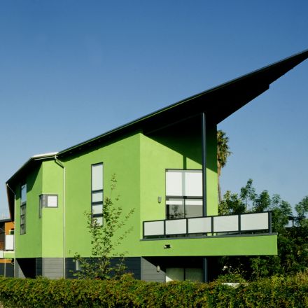 A green house surrounded by lush greenery, showcasing its vibrant color and inviting atmosphere.