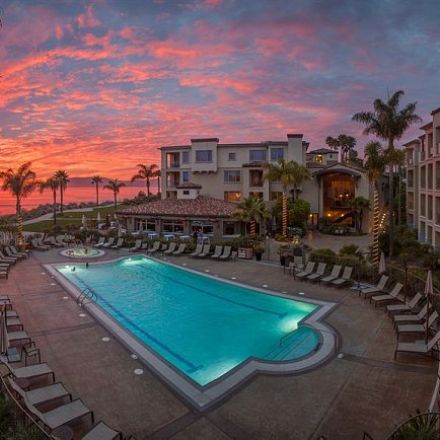 A serene resort pool illuminated by the warm hues of sunset, reflecting the vibrant colors of the evening sky.
